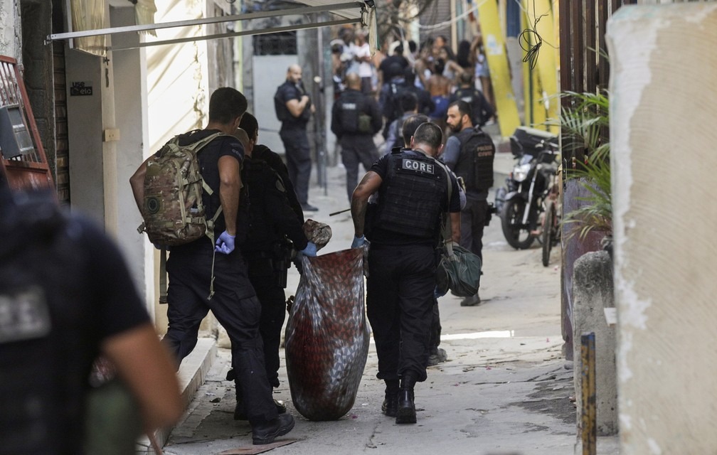 Corpo de morador do Jacarezinho retirado num saco pela polícia (Foto: RICARDO MORAES / REUTERS