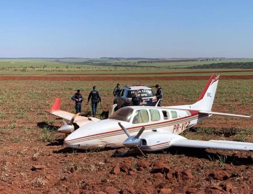 Policiais militares ao lado do avião abandonado em lavoura de cana, em Ivinhema (Foto: Divulgação) 