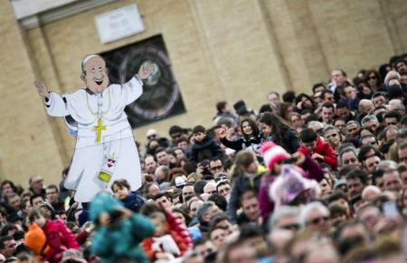 Uma caricatura representando o papa Francisco é erguida em meio ao fiéis durante a missa do Angelus, na Praça de São Pedro, Vaticano.